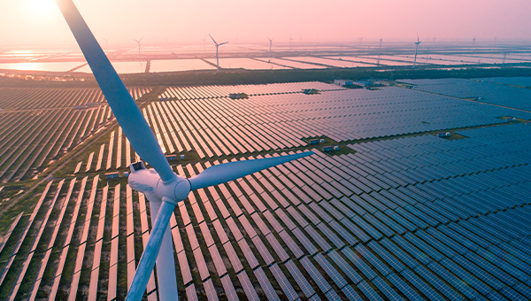 Luchtfoto van een windturbine boven een groot veld zonnepanelen